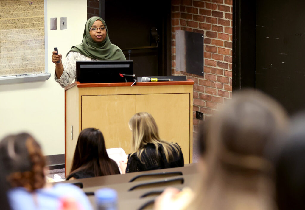 Dr. Qaali Hussein speaking at a podium at a conference